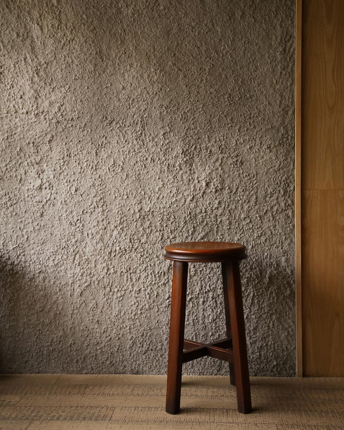 Earth tone render wall with wooden stool
